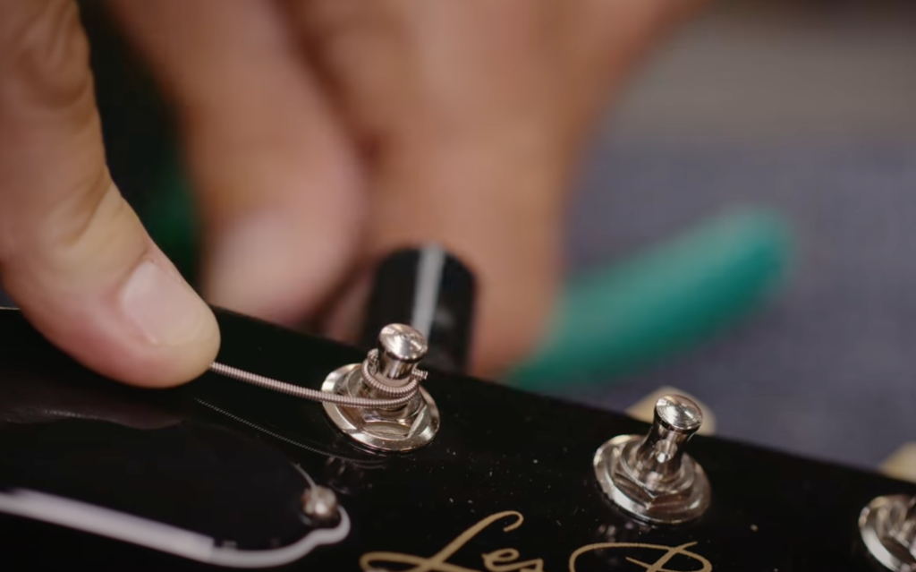 Master Luthier Jim DeCola winds the string through the tuning post while applying downward pressure on the string while changing electric guitar strings